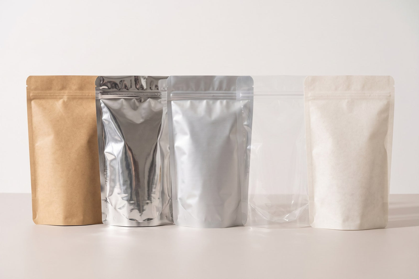 Aynı ölçüdeki beş doypack farklı malzemelerde: kraft, metalize, alüminyum, şeffaf ve bitki özlü